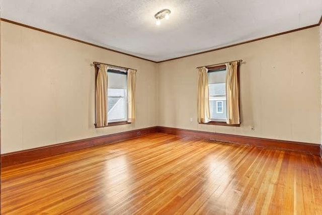 spare room with crown molding, baseboards, a healthy amount of sunlight, and light wood finished floors