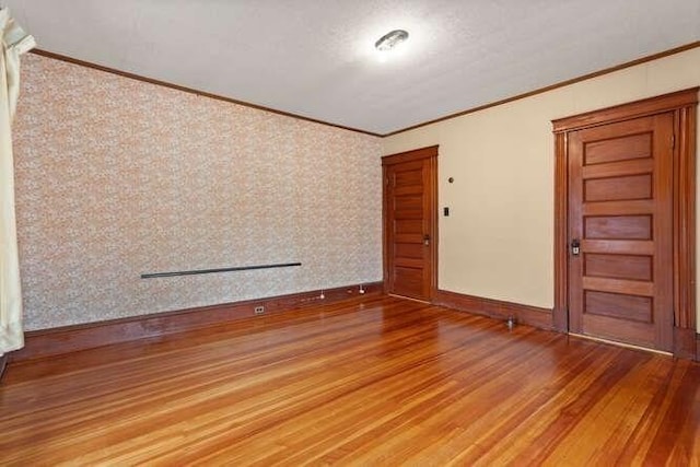 spare room with baseboards, ornamental molding, and wood finished floors