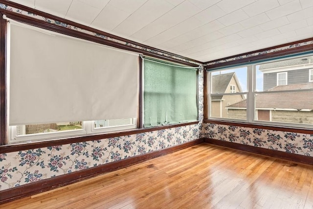 spare room with wallpapered walls, baseboards, and hardwood / wood-style flooring