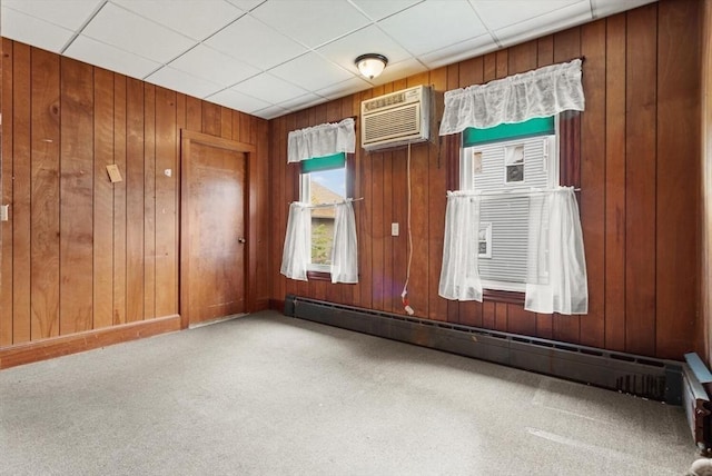 carpeted spare room with wooden walls, a wall mounted AC, and a baseboard heating unit