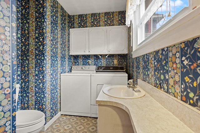 bathroom with independent washer and dryer, a sink, toilet, wallpapered walls, and baseboards