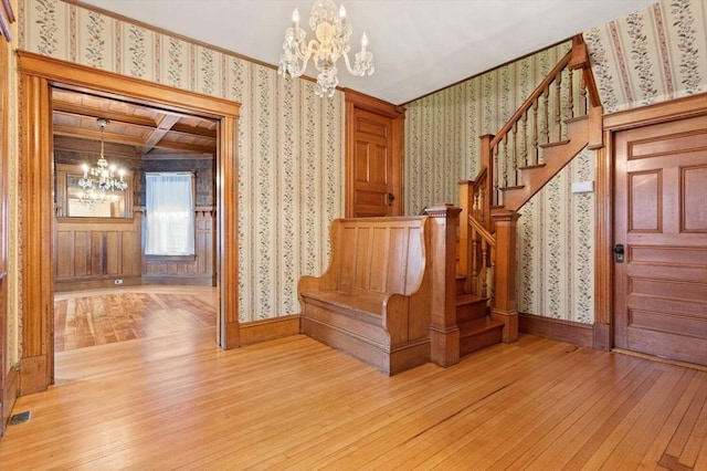 stairs featuring ornamental molding, baseboards, wallpapered walls, hardwood / wood-style flooring, and a notable chandelier