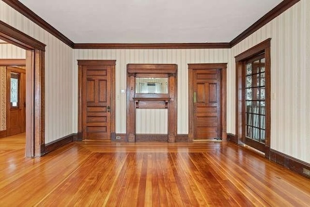 unfurnished living room featuring wallpapered walls, ornamental molding, wood finished floors, and a wealth of natural light