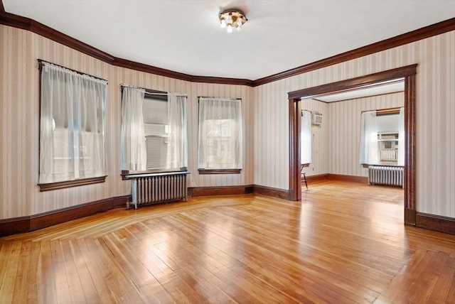 spare room featuring radiator, ornamental molding, wood-type flooring, and wallpapered walls