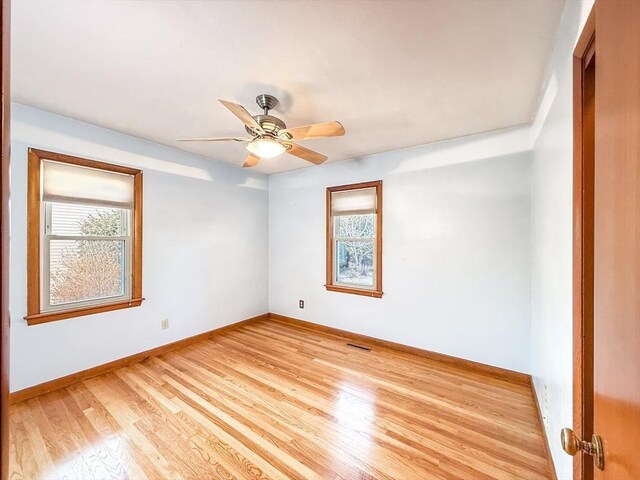 empty room featuring light wood finished floors, visible vents, a ceiling fan, and baseboards