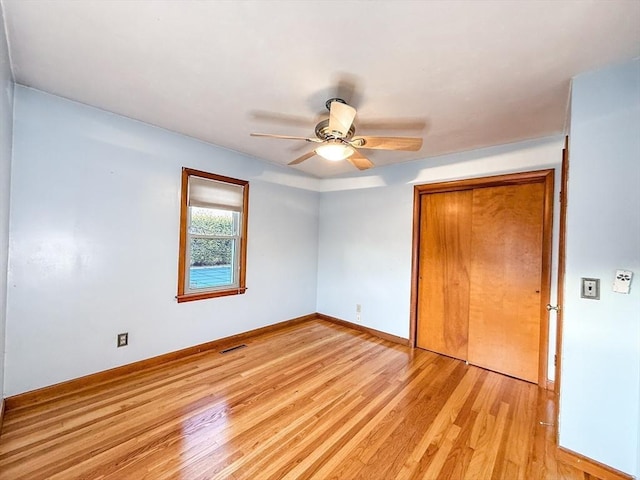 unfurnished bedroom featuring light wood-type flooring, visible vents, a closet, baseboards, and ceiling fan