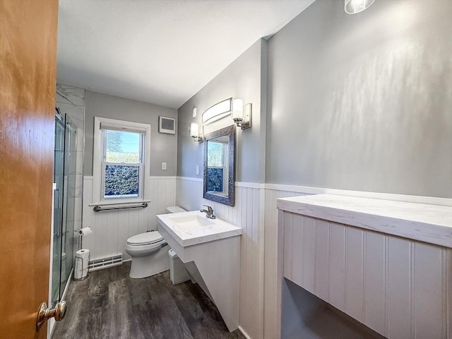 bathroom featuring toilet, wood finished floors, a wainscoted wall, and a stall shower