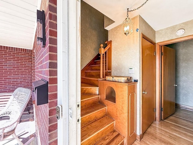 staircase featuring brick wall and wood finished floors