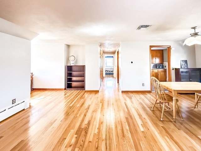 dining area featuring light wood finished floors, visible vents, baseboards, and a baseboard radiator