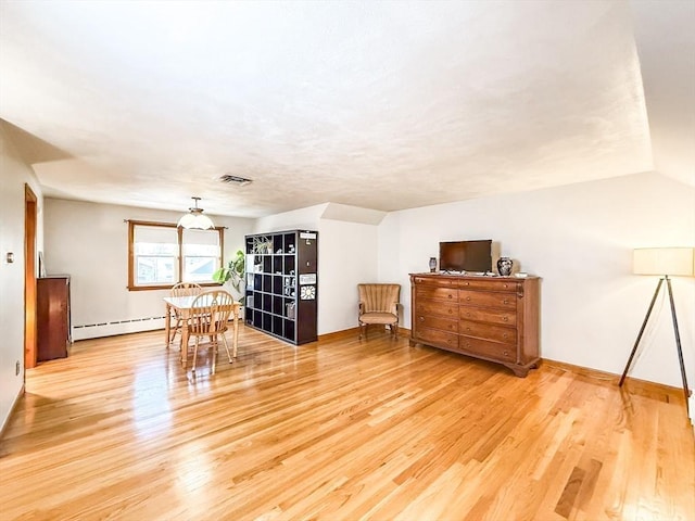 interior space with visible vents, lofted ceiling, baseboard heating, and wood finished floors