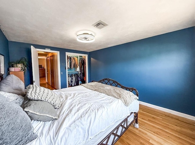 bedroom featuring visible vents, baseboards, a closet, and wood finished floors