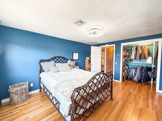 bedroom featuring visible vents, baseboards, a closet, and wood finished floors