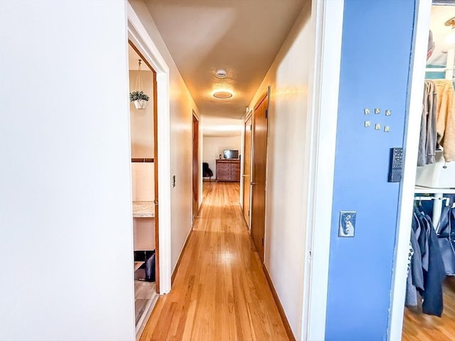 corridor featuring light wood-style floors and baseboards