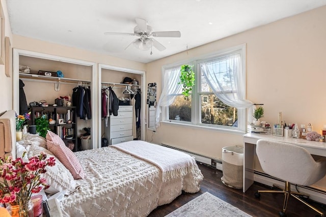 bedroom with dark wood-type flooring, a baseboard radiator, ceiling fan, and multiple closets