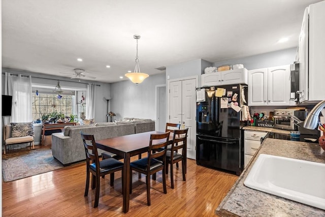 kitchen featuring pendant lighting, black fridge, ceiling fan, light hardwood / wood-style floors, and white cabinetry