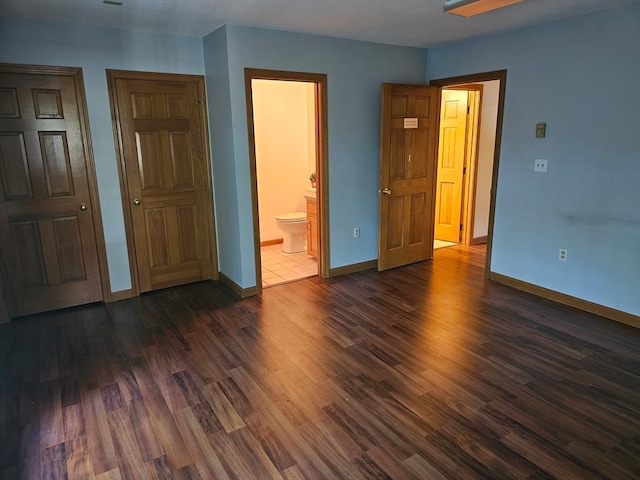 unfurnished bedroom with dark wood-type flooring and ensuite bath