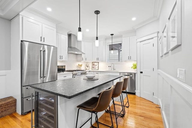 31 Henderson St Unit 1, Arlington, MA 02474 - kitchen featuring appliances with stainless steel finishes, wall chimney range hood, a breakfast bar, wine cooler, and white cabinets