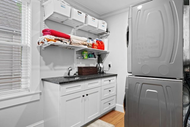 31 Henderson St Unit 1, Arlington, MA 02474 - laundry area with stacked washer / drying machine, crown molding, light wood-style floors, baseboards, and cabinet space