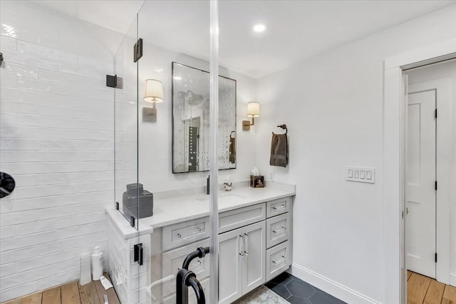 bathroom featuring tiled shower, vanity, and baseboards