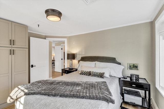 bedroom featuring a baseboard heating unit, light wood-type flooring, and crown molding