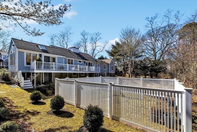 back of house with a fenced backyard, a residential view, a chimney, roof with shingles, and a wooden deck