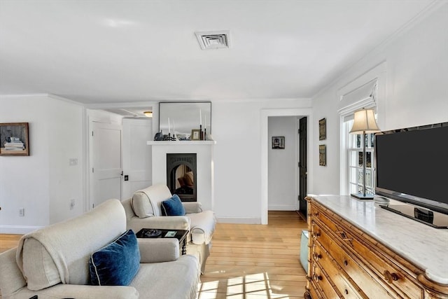 living area with visible vents, a fireplace, light wood-style flooring, and baseboards