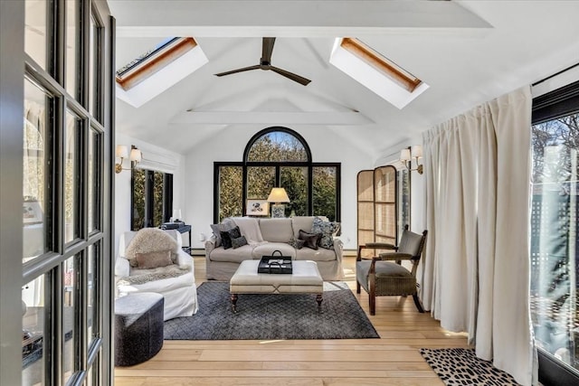 sunroom with vaulted ceiling with skylight, a ceiling fan, and a wealth of natural light