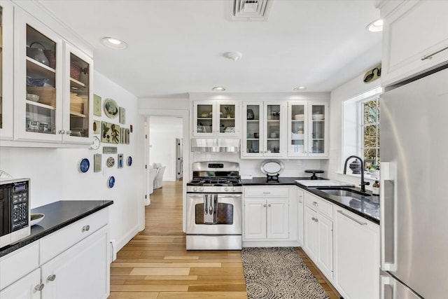 kitchen with a sink, visible vents, white cabinets, appliances with stainless steel finishes, and dark countertops