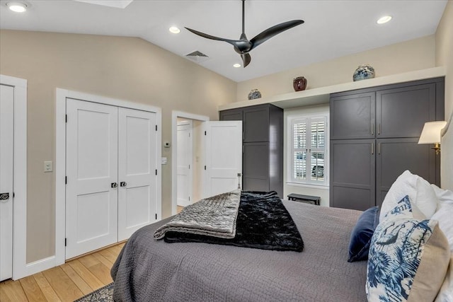 bedroom featuring visible vents, lofted ceiling, light wood-type flooring, two closets, and recessed lighting