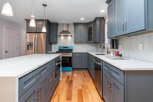 kitchen featuring a center island, sink, hanging light fixtures, appliances with stainless steel finishes, and wall chimney exhaust hood