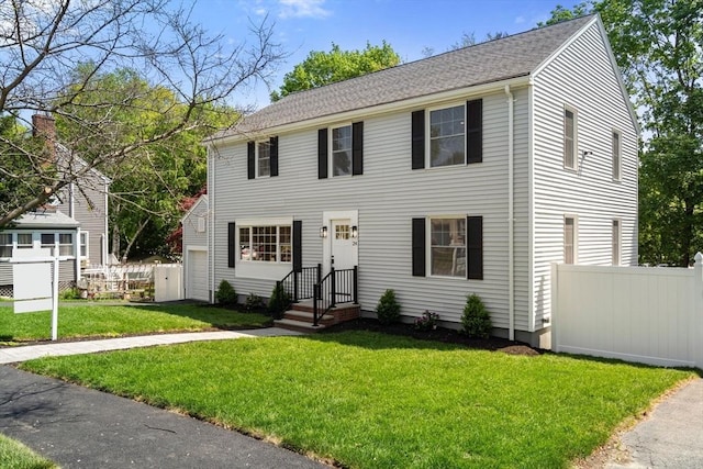 colonial house with a shingled roof and a garage