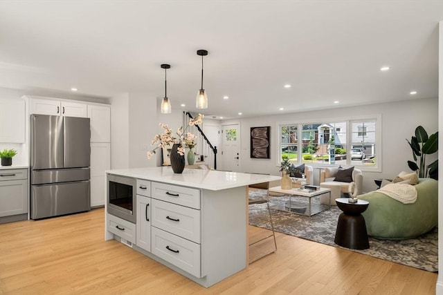 kitchen with appliances with stainless steel finishes, light wood finished floors, light countertops, open floor plan, and recessed lighting