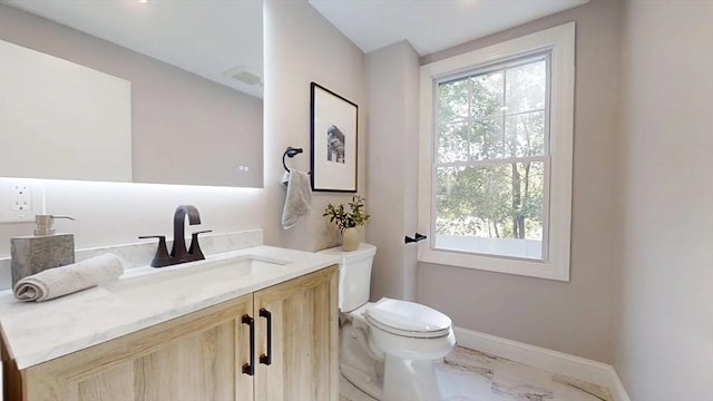 bathroom with marble look tiles, toilet, vanity, and baseboards