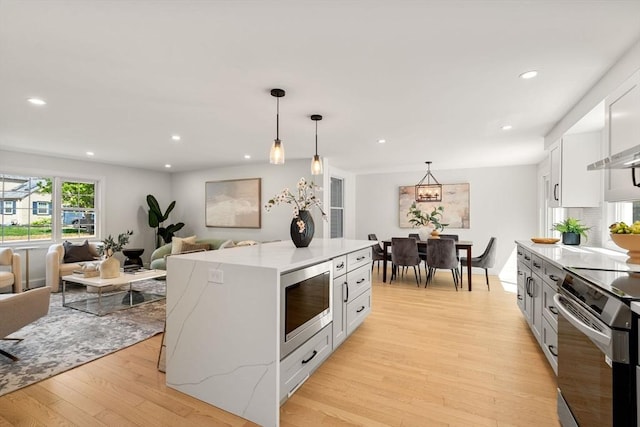 kitchen with appliances with stainless steel finishes, light wood finished floors, light countertops, recessed lighting, and open floor plan