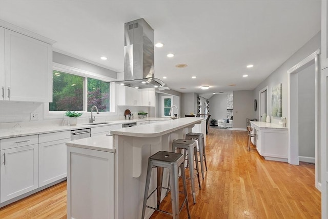 14 Preservation Way, Westford, MA 01886 - kitchen with island exhaust hood, a breakfast bar area, white cabinets, a sink, and light wood finished floors