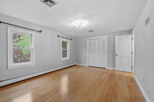 14 Preservation Way, Westford, MA 01886 - unfurnished bedroom featuring a baseboard radiator, light wood-style flooring, a closet, baseboards, and a textured ceiling