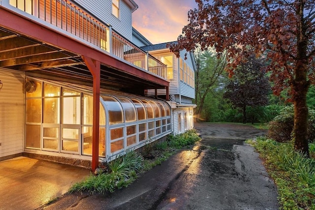 14 Preservation Way, Westford, MA 01886 - property exterior at dusk featuring a sunroom, asphalt driveway, and a balcony