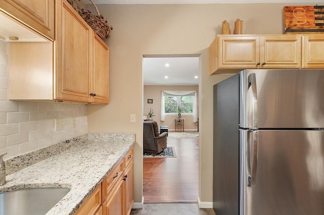 425 Main St Unit 8B, Hudson, MA 01749 - kitchen with freestanding refrigerator, light brown cabinetry, light stone counters, decorative backsplash, and light wood-style flooring