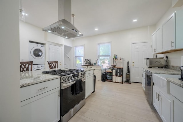 36-38 Elm Hill Park, Boston, MA 02121 - kitchen with appliances with stainless steel finishes, island range hood, stacked washing machine and dryer, light stone countertops, and white cabinetry