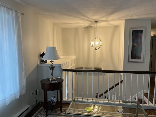 hallway with dark hardwood / wood-style floors, a chandelier, a textured ceiling, and a baseboard heating unit