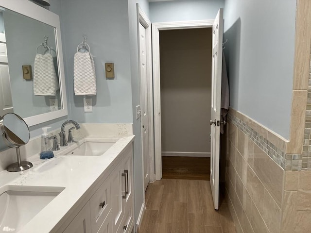 bathroom with wood-type flooring, vanity, and tile walls