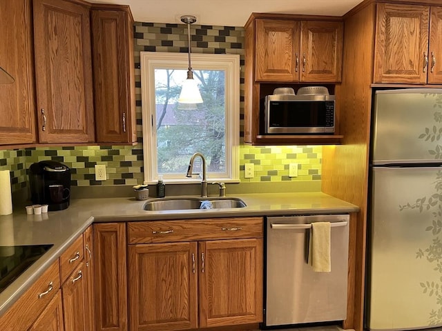 kitchen featuring appliances with stainless steel finishes, tasteful backsplash, pendant lighting, and sink