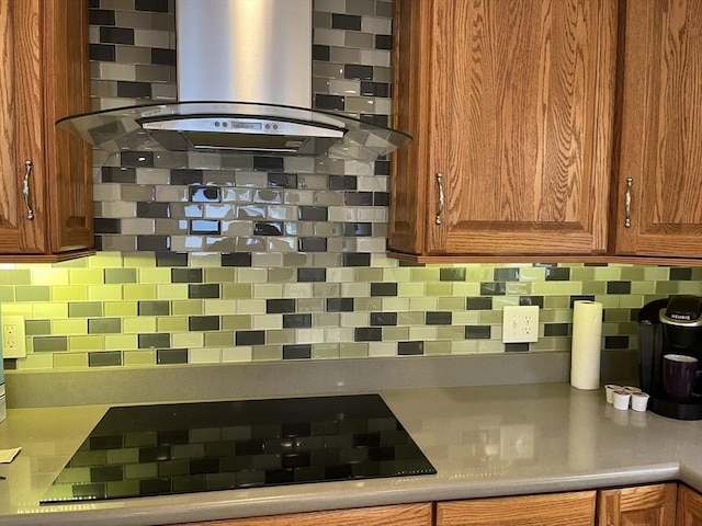 kitchen featuring black electric stovetop, island range hood, and tasteful backsplash