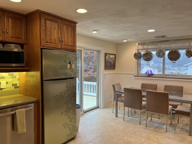 kitchen with backsplash, stainless steel appliances, and light tile patterned flooring