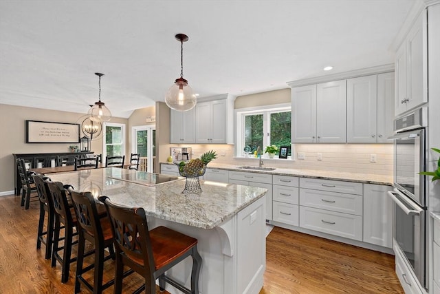 148 Old Schoolhouse Ln, Hanover, MA 02339 - kitchen featuring stainless steel double oven, black electric cooktop, tasteful backsplash, a kitchen island, and wood finished floors