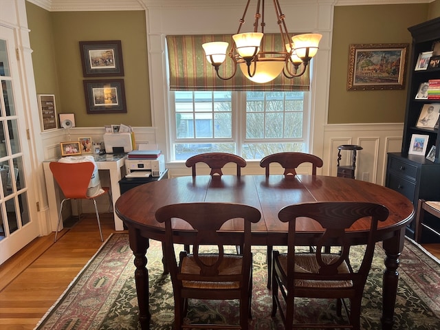 dining area featuring a notable chandelier, ornamental molding, a wealth of natural light, and hardwood / wood-style flooring