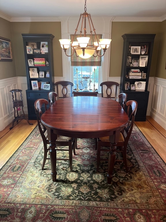 dining space with light hardwood / wood-style floors, ornamental molding, and a chandelier