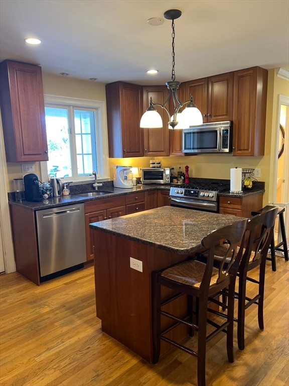 kitchen with hanging light fixtures, a center island, a breakfast bar, stainless steel appliances, and light hardwood / wood-style floors