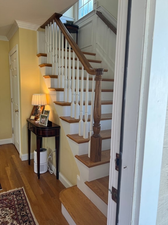 stairway featuring ornamental molding and hardwood / wood-style flooring