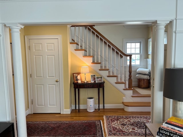 stairway with decorative columns and dark hardwood / wood-style flooring